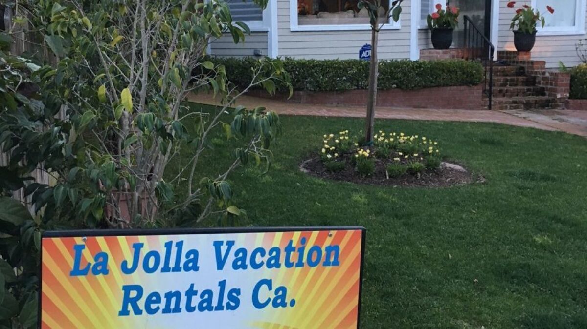 A short-term vacation rental sign is posted in a yard in 2017. 