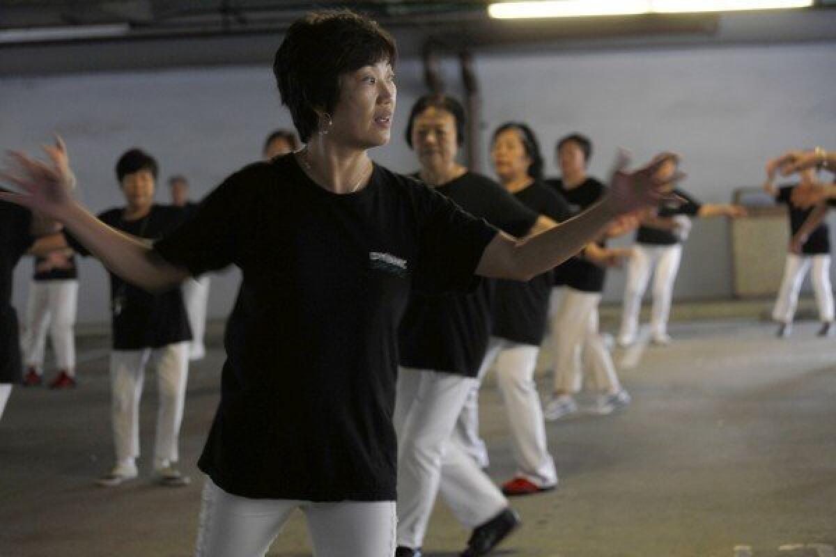 Kit Cheung leads members of the Dynamic Line Dance group, which meets in a parking garage at the Monterey Park library.
