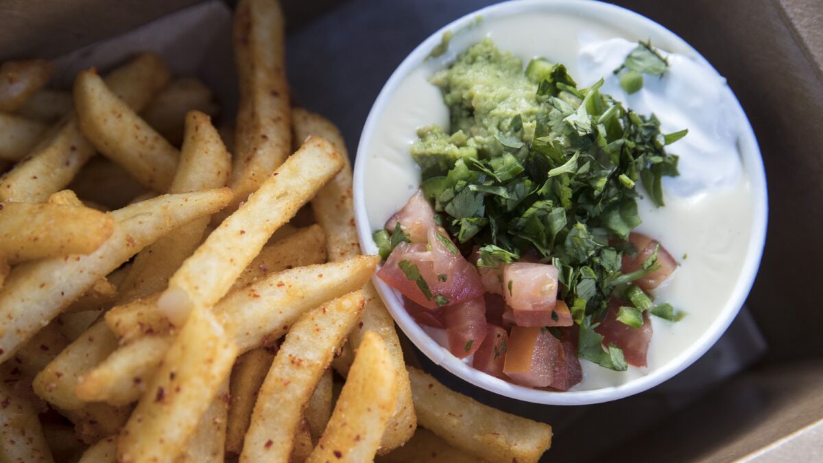 The Abbot Kinney white queso with jalapeño, house pico, house guacamole, sour cream and cilantro, served up with fries at the Queso Truck.