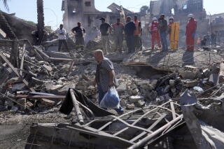 A man carries his belonging at the site of Israeli airstrikes that destroyed buildings in southern Beirut, Lebanon.