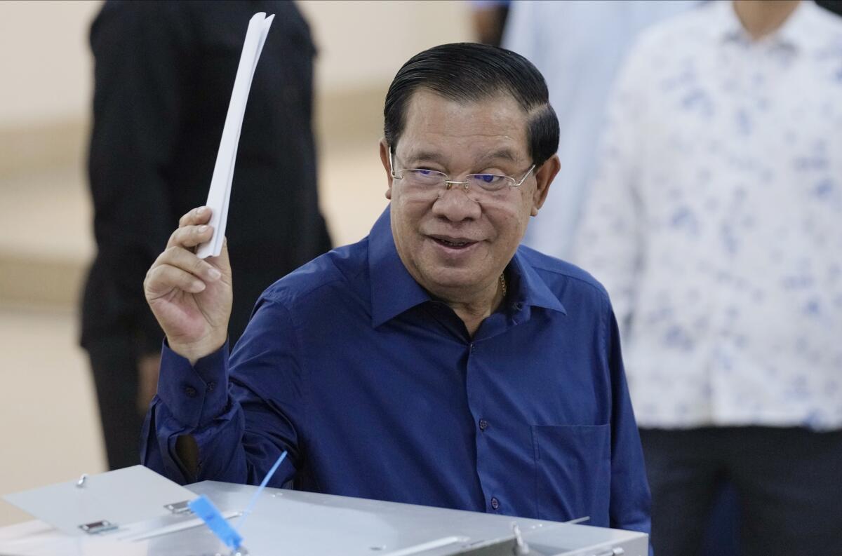Cambodian Prime Minister Hun Sen raises a ballot at a voting center.
