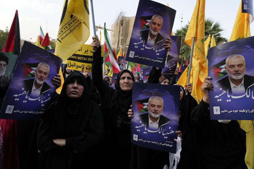 Manifestantes iraníes asisten a una manifestación para condenar el asesinato del líder de Hamás Ismail Haniyeh mientras sostienen pancartas suyas en las que se lee en árabe: "¡Felicidades Haniyeh!" en la plaza Felestin (Palestina) de Teherán, Irán, miércoles 31 de julio de 2024. (AP Foto/Vahid Salemi)