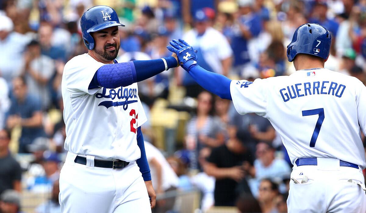 The Dodgers' Adrian Gonzalez gets a high five from Alex Guerrero on his way back to the dugout after Gonzalez scored in the fourth inning against the Colorado Rockies at Dodger Stadium on May 17.
