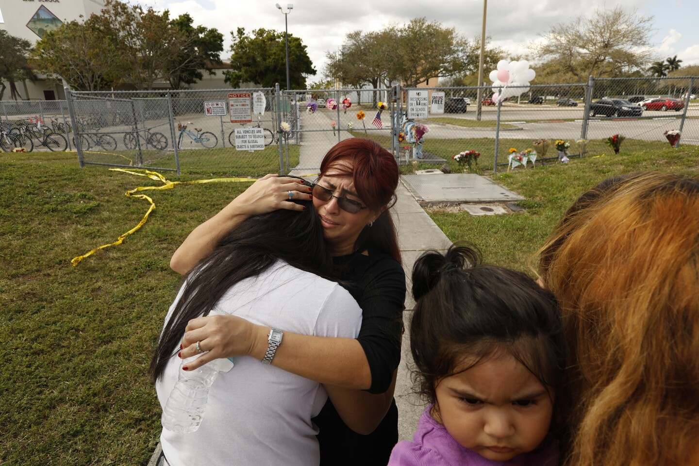 Abigail Avioa, a senior at Marjorie Stoneman Douglas High School, her back to camera, is prayed over in front of the school on Sunday, Feb. 18, 2018.