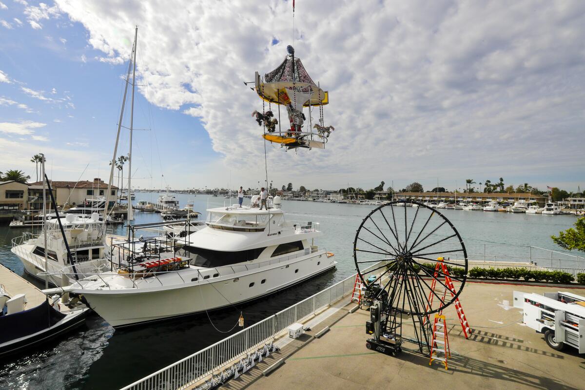 A boat parade decoration is lowered by crane onto a yacht in Newport Beach.