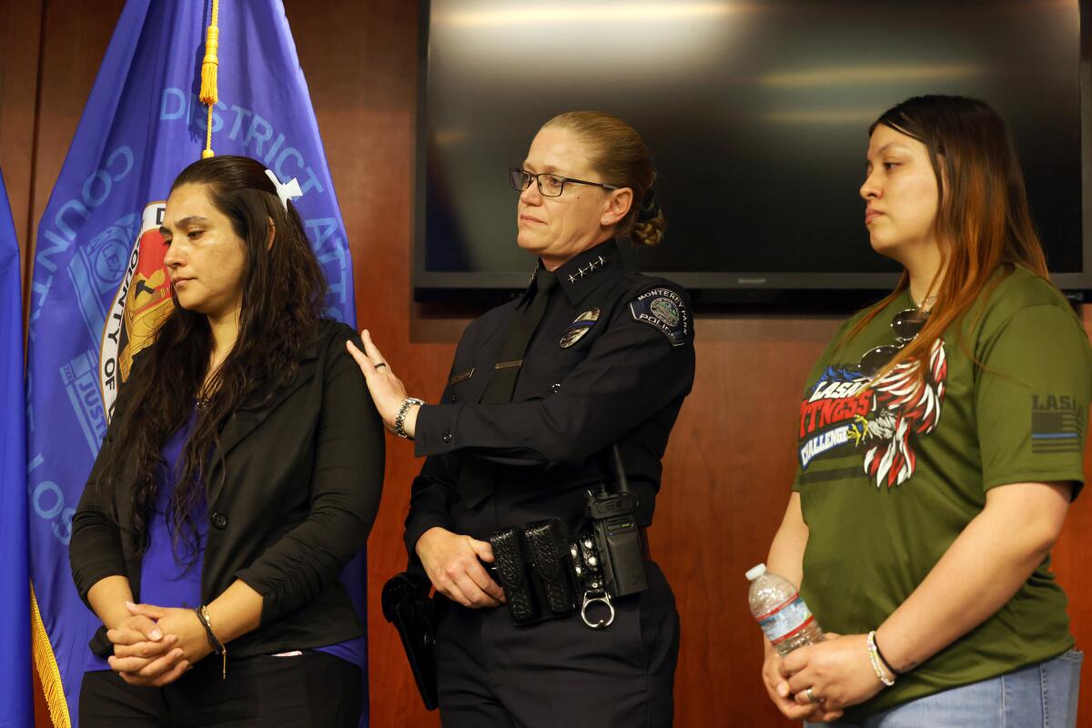 An officer puts her hand on a woman's shoulder as another woman stands next to her.