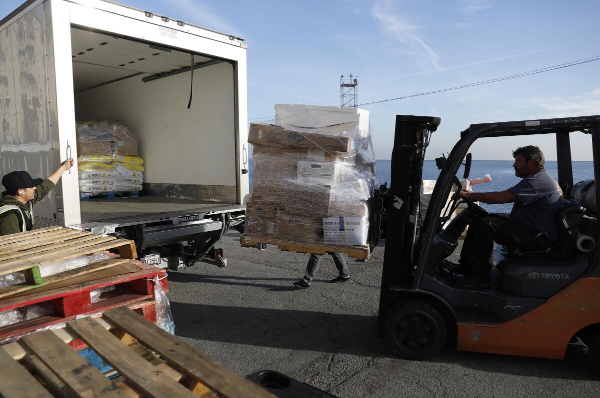 Truck driver Jesse Velasquez, left, watches as orders are unloaded.