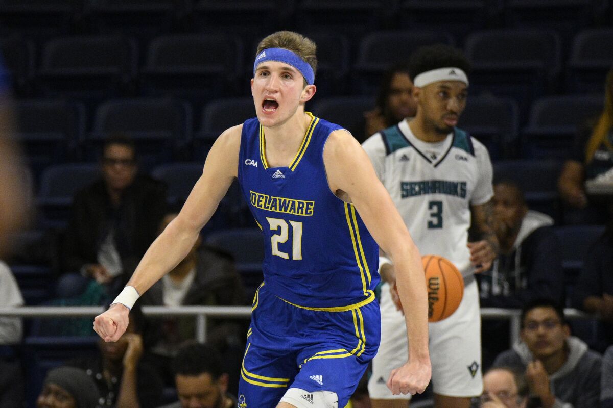 Delaware forward Andrew Carr (21) reacts after his dunk during the first half of an NCAA college basketball game in the championship of the Colonial Athletic Association conference tournament, Tuesday, March 8, 2022, in Washington. UNC Wilmington guard James Baker is at back. (AP Photo/Nick Wass)