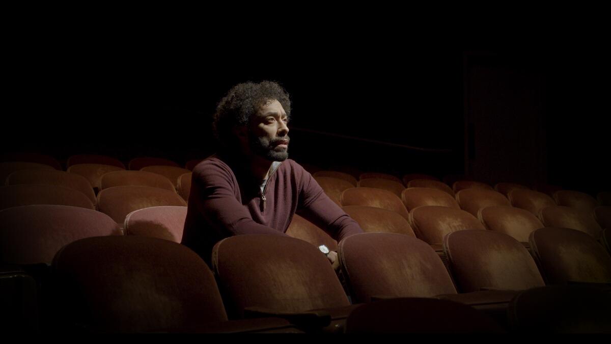 Actor William DeMeritt sits inside a theater