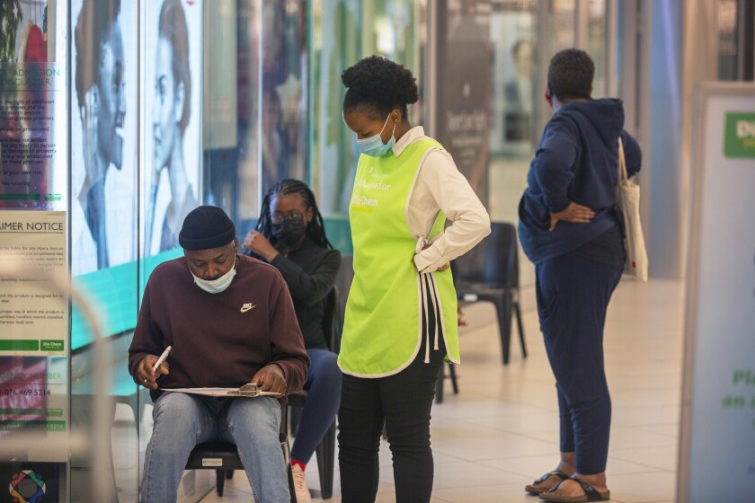 Varias personas esperan para vacunarse contra el COVID-19 en un centro comercial en Johannesburgo, Sudáfrica.