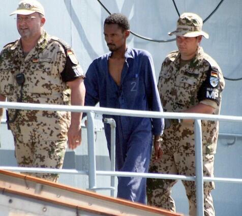 German Military Police escort one of the seven suspected Somali pirates