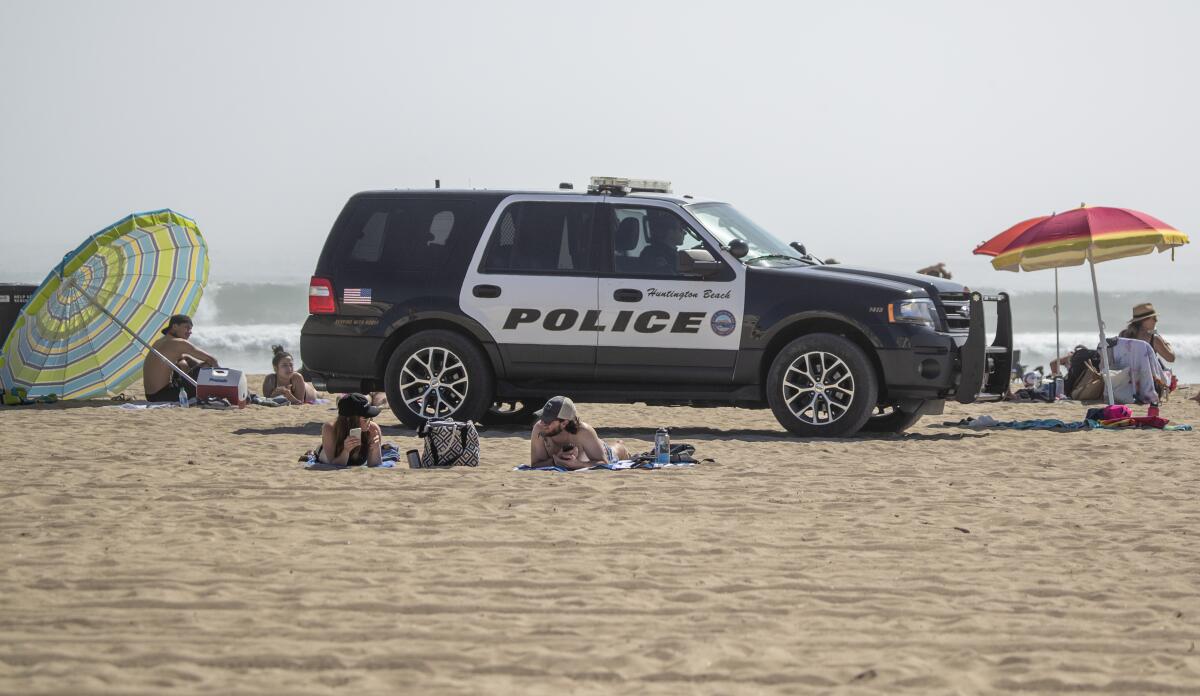 Huntington Beach police patrol the beach near the pier Saturday as thousands of people enjoy a warm, sunny day amid stay-at-home and social-distancing mandates to curb the coronavirus outbreak.
