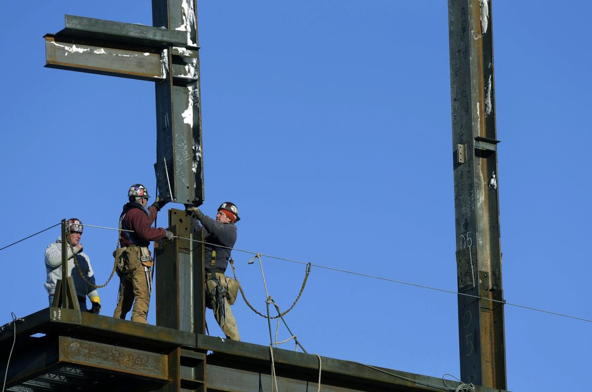 Workers guide a vertical girder into place during construction of a building in Boston.