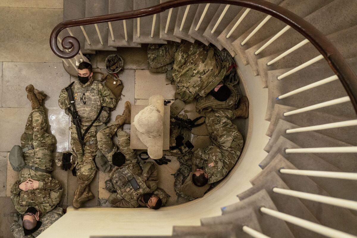 a group of people in military uniform sleep on a stone floor