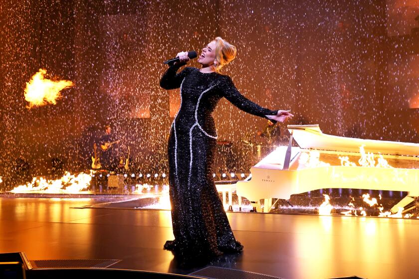 Adele leans back as she sings on a stage filled with water and fire