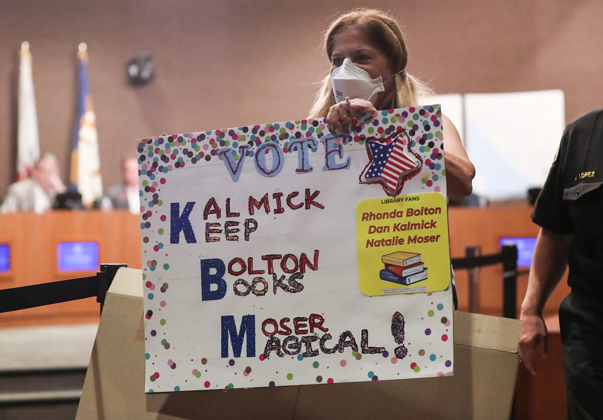 Public speaker Barbara Shapiro walks away from the podium with her sign during Tuesday's meeting.