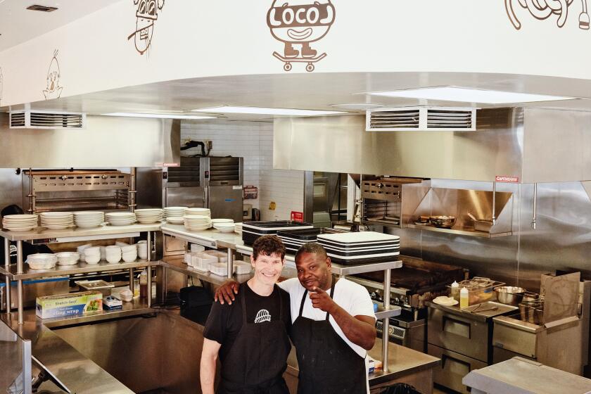 Daniel Patterson and Keith Corbin stand in the open kitchen of Locol in Watts. Corbin points at the camera.