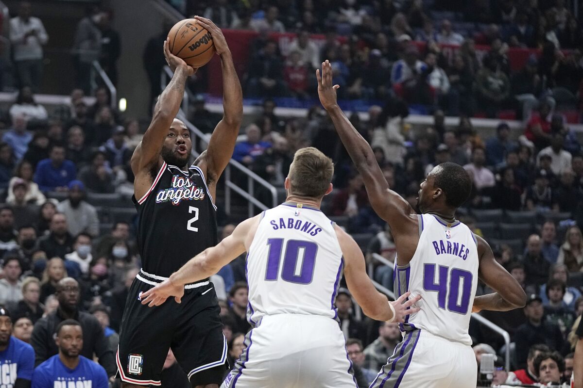 Clippers forward Kawhi Leonard shoots over Sacramento Kings forwards Domantas Sabonis and forward Harrison Barnes.