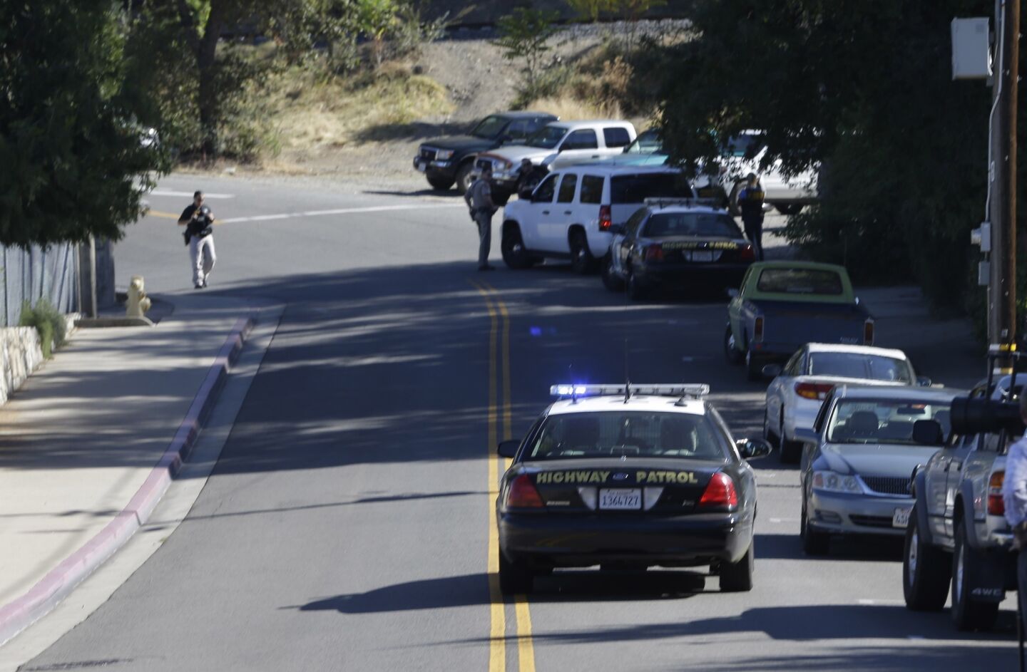 A California Highway Patrol car and other law enforcement vehicles set up a roadblock near Placer High School leading to a rural area where authorities were searching for an assailant who shot three sheriff's deputies in two Northern California counties.