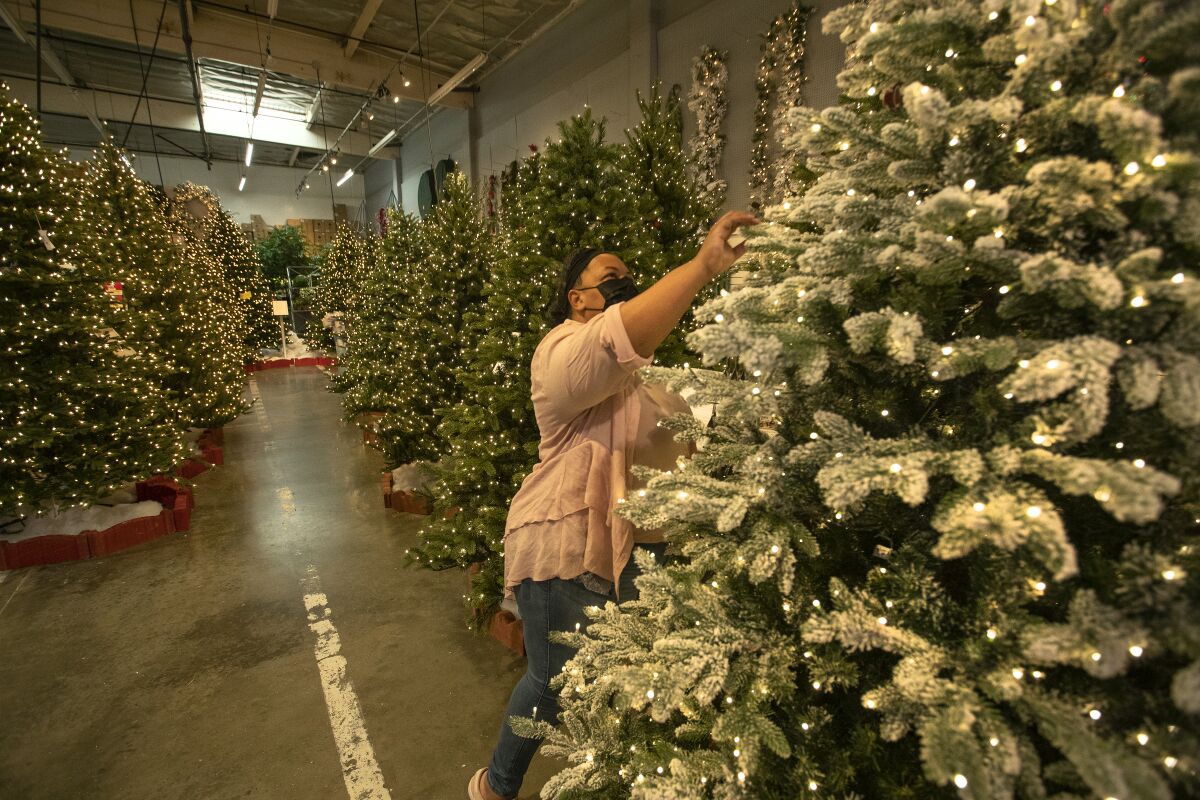 A woman looks at an artificial Christmas tree in a store's warehouse