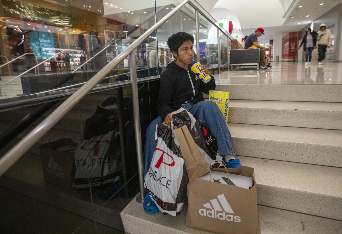 Pablo Santiago, 14, takes a break from shopping on Black Friday at the Glendale Galleria.