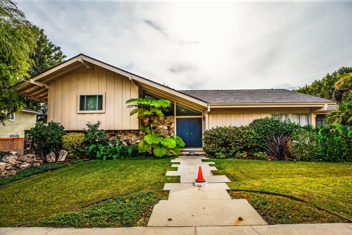 The "Brady Bunch" house in Studio City  is a tan split-level with a concrete path leading to a blue door