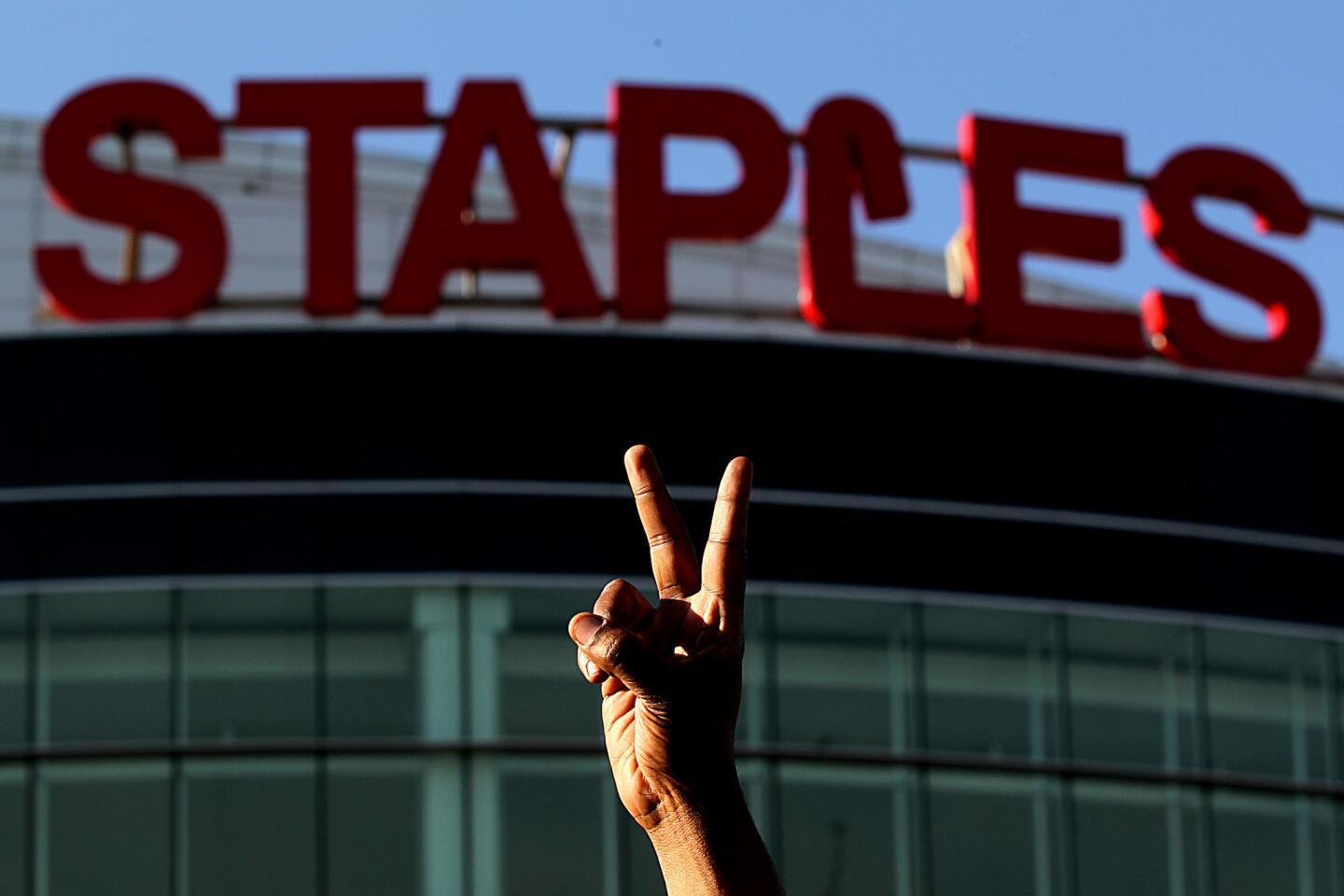 A protester flashes a victory sign outside of Staples Center before the start of Game 5.