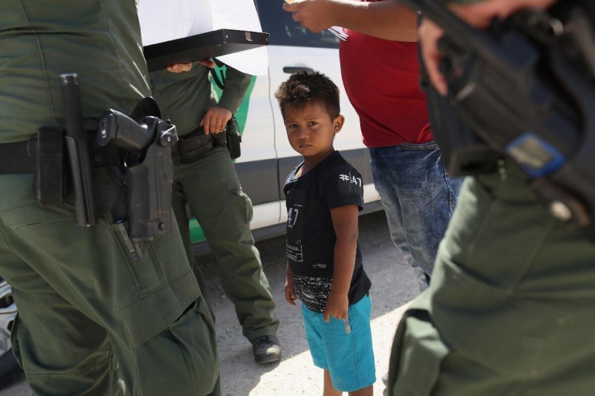 Border Patrol agents take a father and son into custody near the U.S.-Mexico border on Tuesday near Mission, Texas.