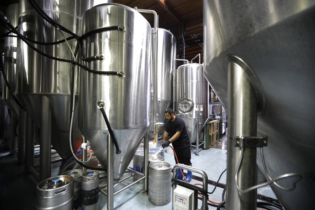 Cellarman Steve Quinteros, dwarfed by fermenting tanks, washes kegs at El Segundo Brewing Co.