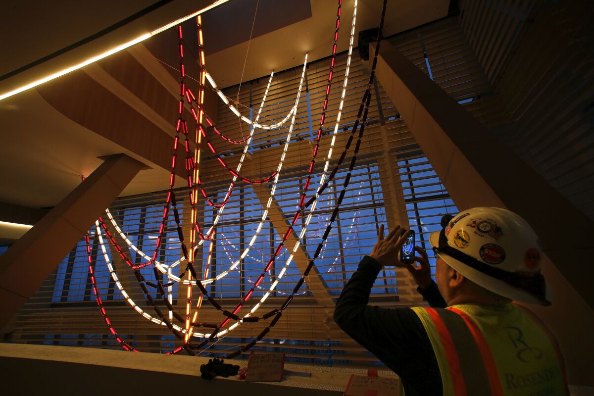 A construction worker photographs the three-story-high chandelier. (Mel Melcon / Los Angeles Times)