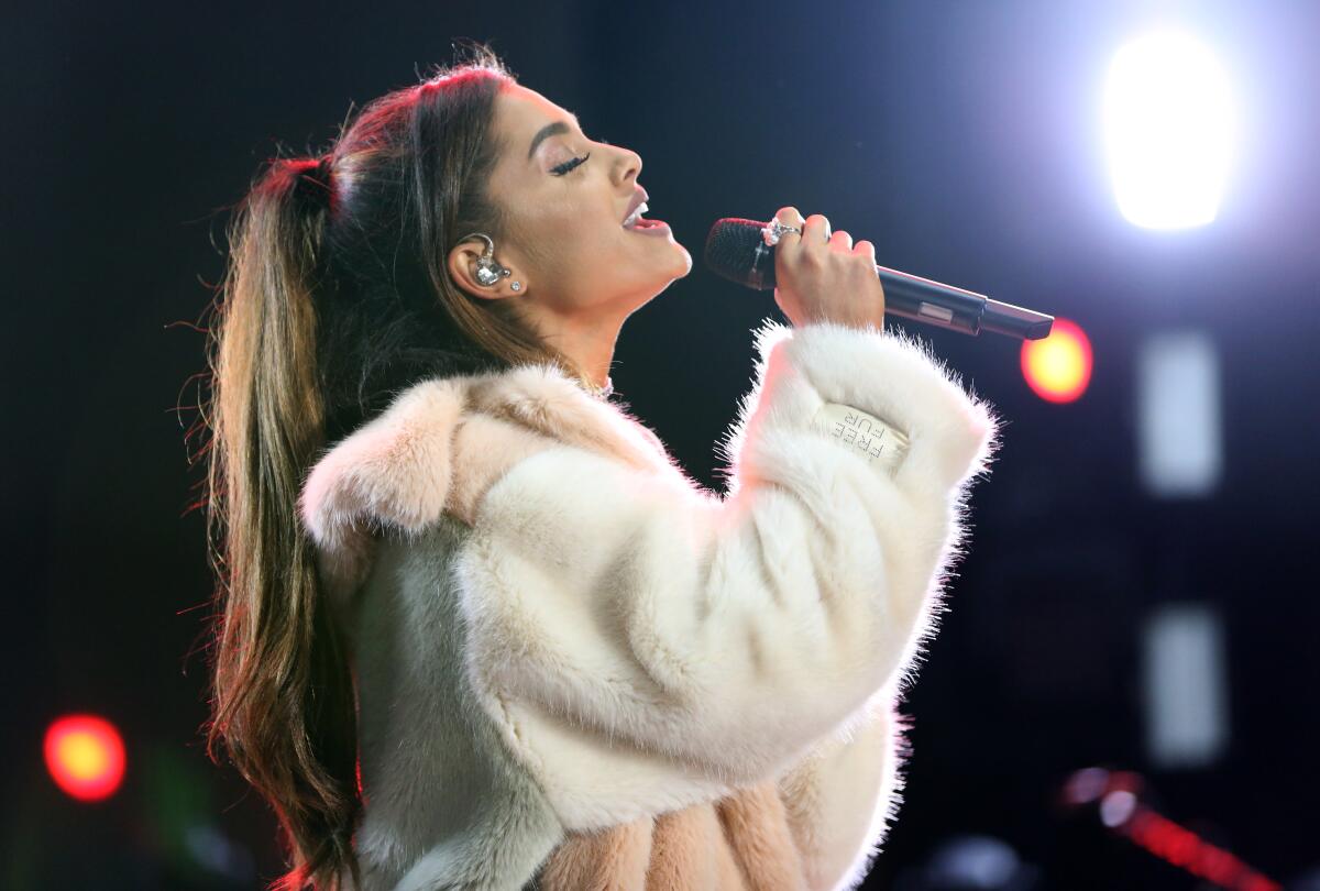 Singer Ariana Grande leans back while singing into a microphone onstage