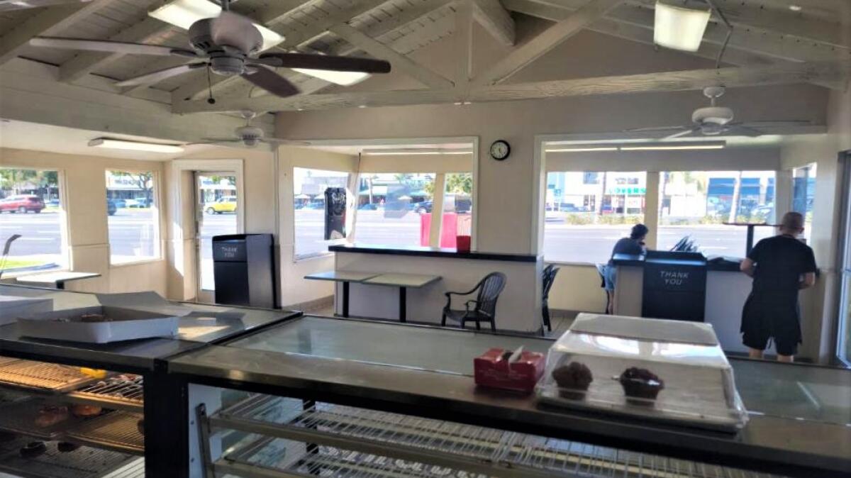 The last customer served at Oh Those Donuts in Costa Mesa dines outdoors as employees prepare to close up after 39 years.