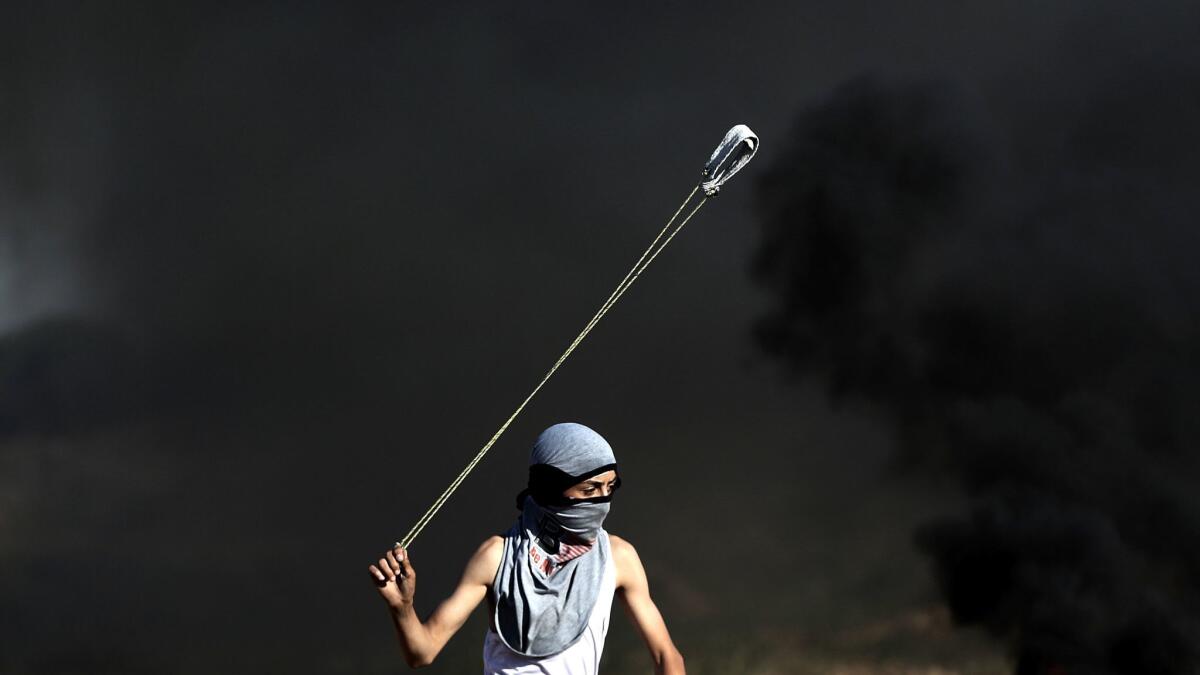 A Palestinian protester throws a stone during clashes with Israeli troops after a protest in support of Palestinian prisoners on hunger strike in Israeli jails, near the border between Israel and east Gaza Strip, 26 May 2017