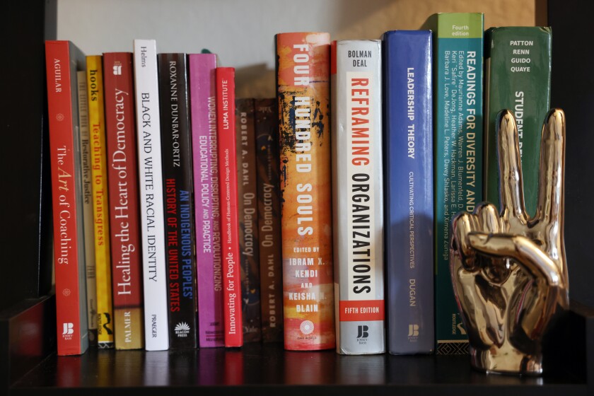A shelf filled with nonfiction books and a gold figure of a hand holding two fingers up in a peace sign. 
