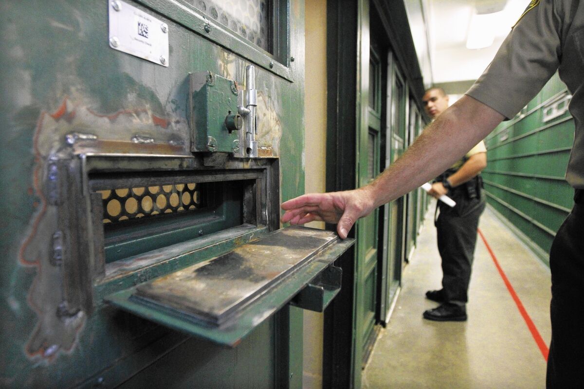 Deputy Stephen Vasquez points out changes to the food tray slots to prevent inmates from throwing waste during a tour of "gassers' alley" at the Men's Central Jail.