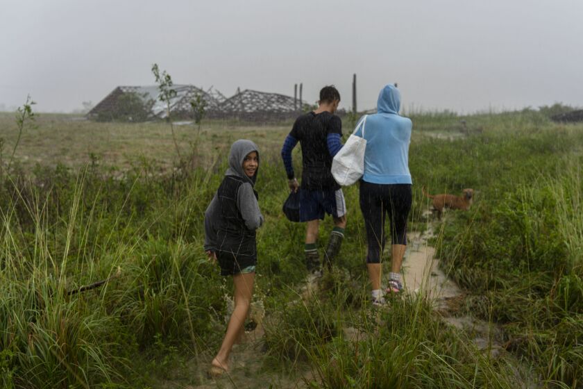 Una familia camina bajo la lluvia en busca de un refugio luego de que su casa se inundó cuando el huracán Ian azotó la provincia de Pinar del Río, en Cuba, el martes 27 de septiembre de 2022. (AP Foto/Ramon Espinosa)