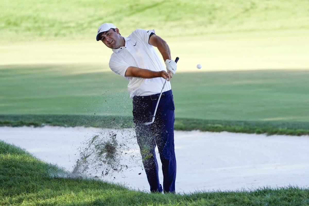 Scottie Scheffler hits from an awkward stance along the 16th fairway.