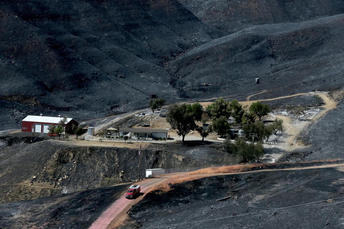 A firefighting vehicle rolls through the burn zone of the Route fire near Castaic.