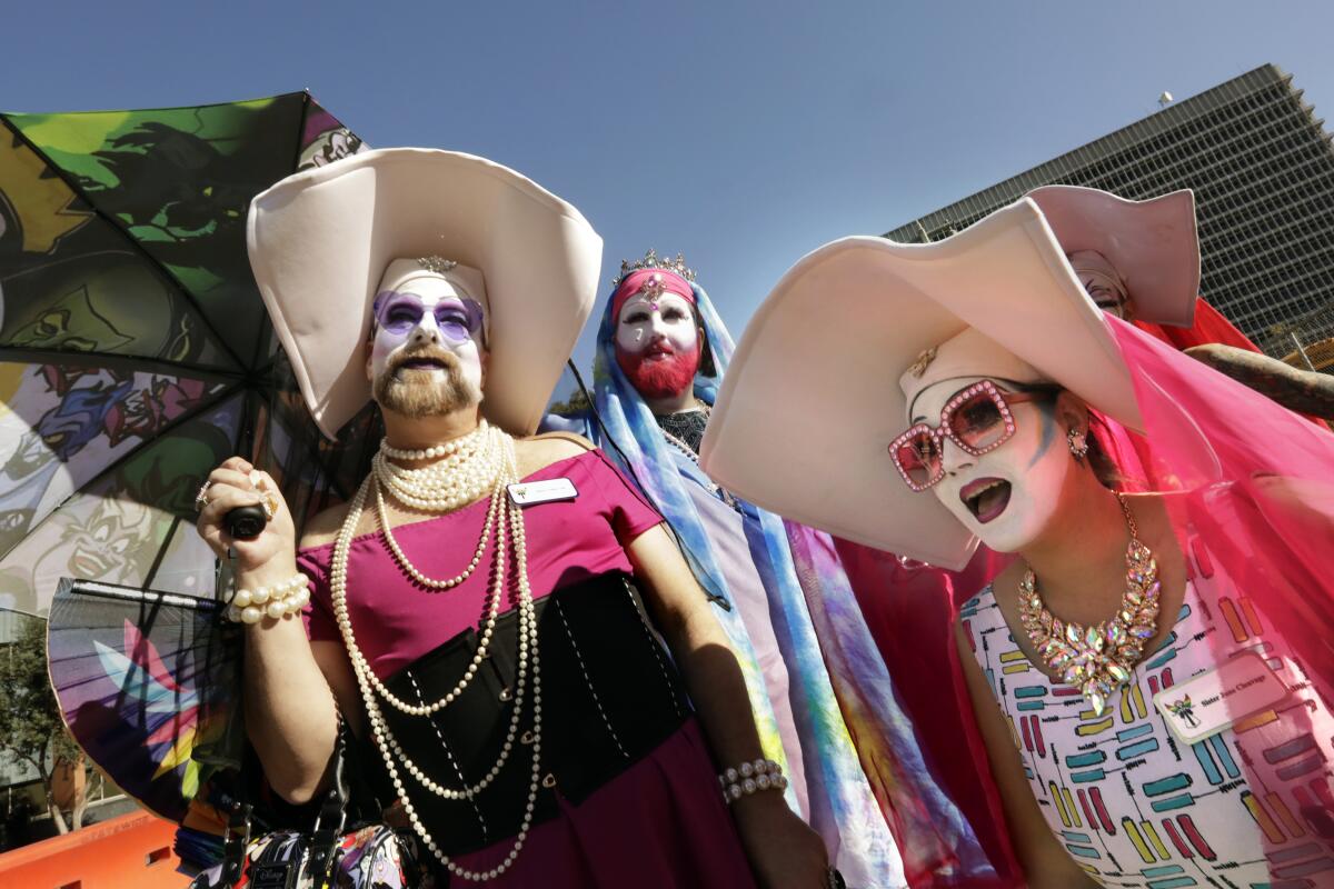 Three drag queens dressed as religious figures, including nuns, walk outside.