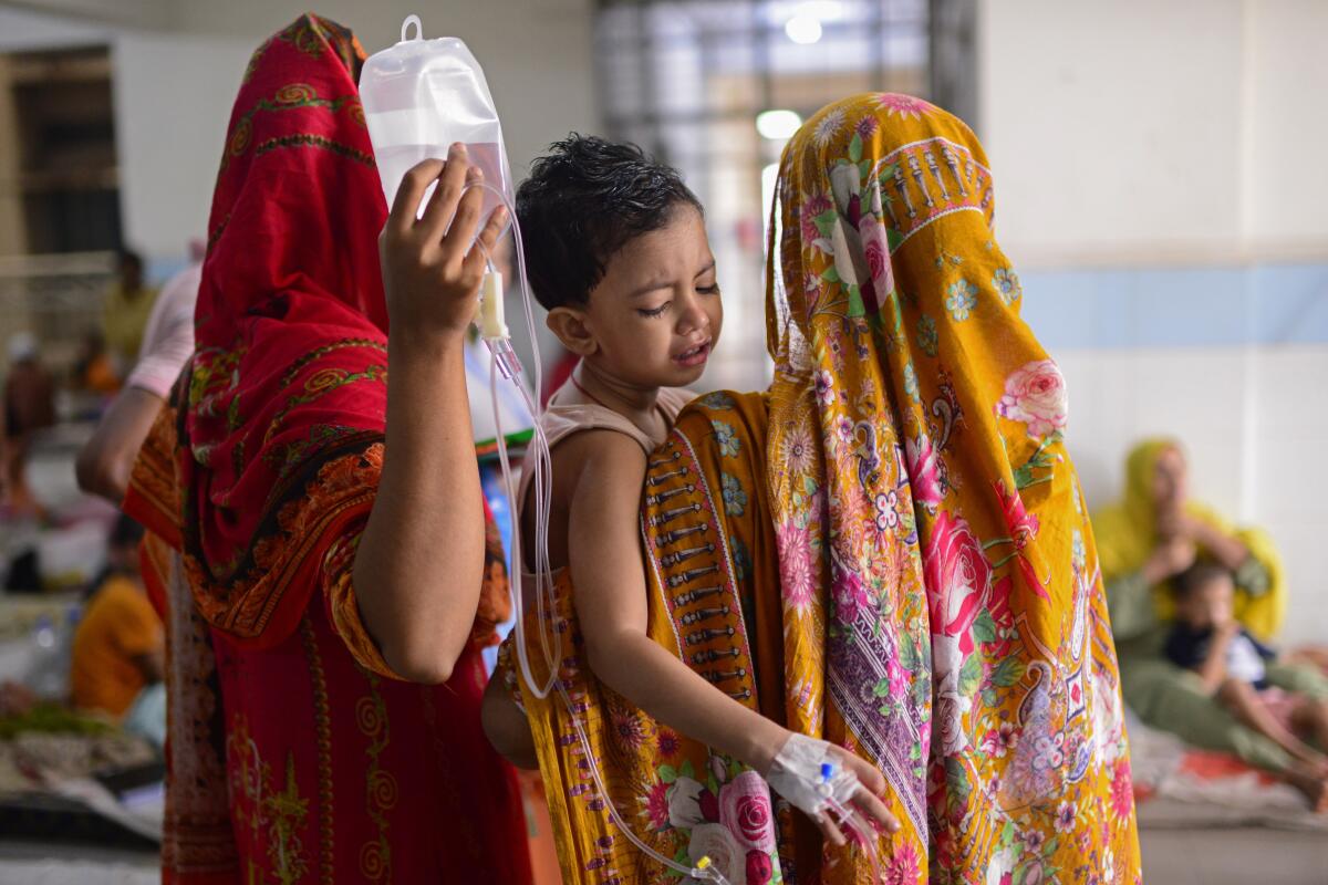 A child is carried by his mother as he receives treatment for dengue at Mugda Medical College and Hospital