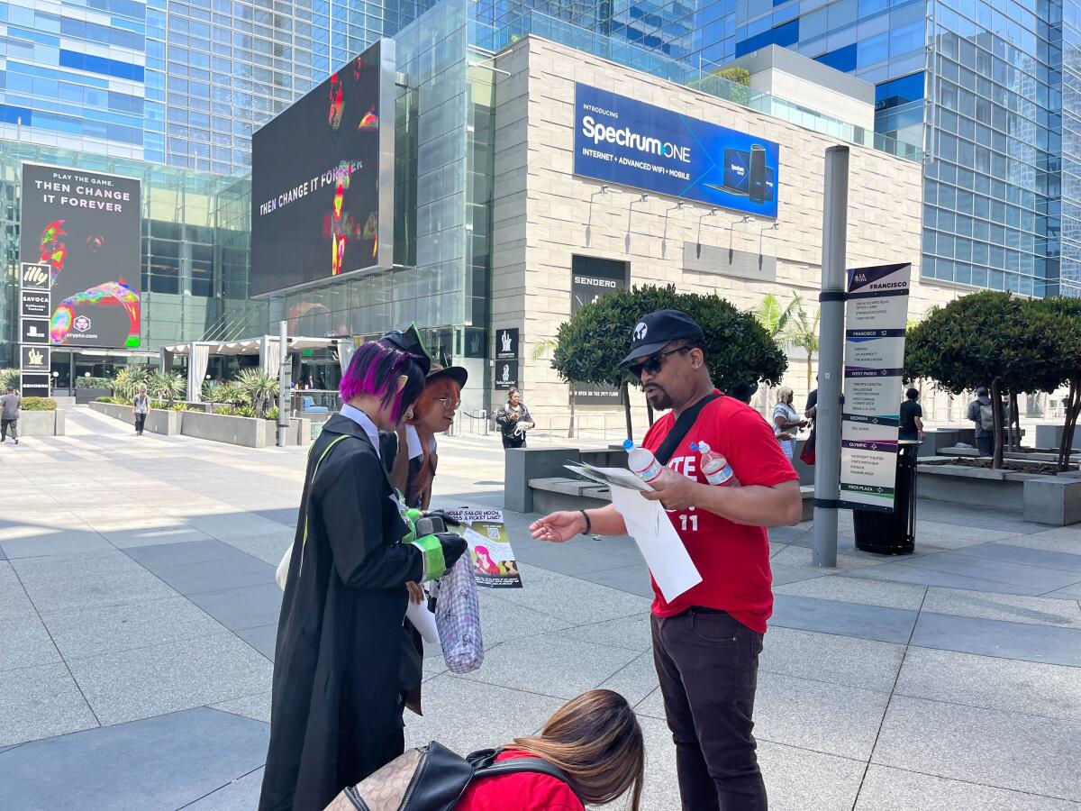 A person hands fliers to people dressed in character outside a convention center