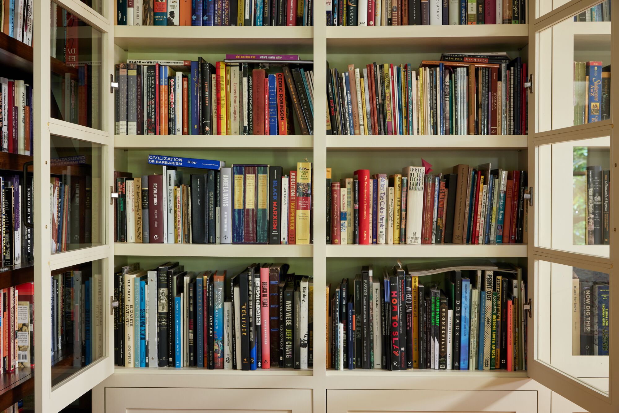 A photo of a bookcase with glass doors, which left wide open.