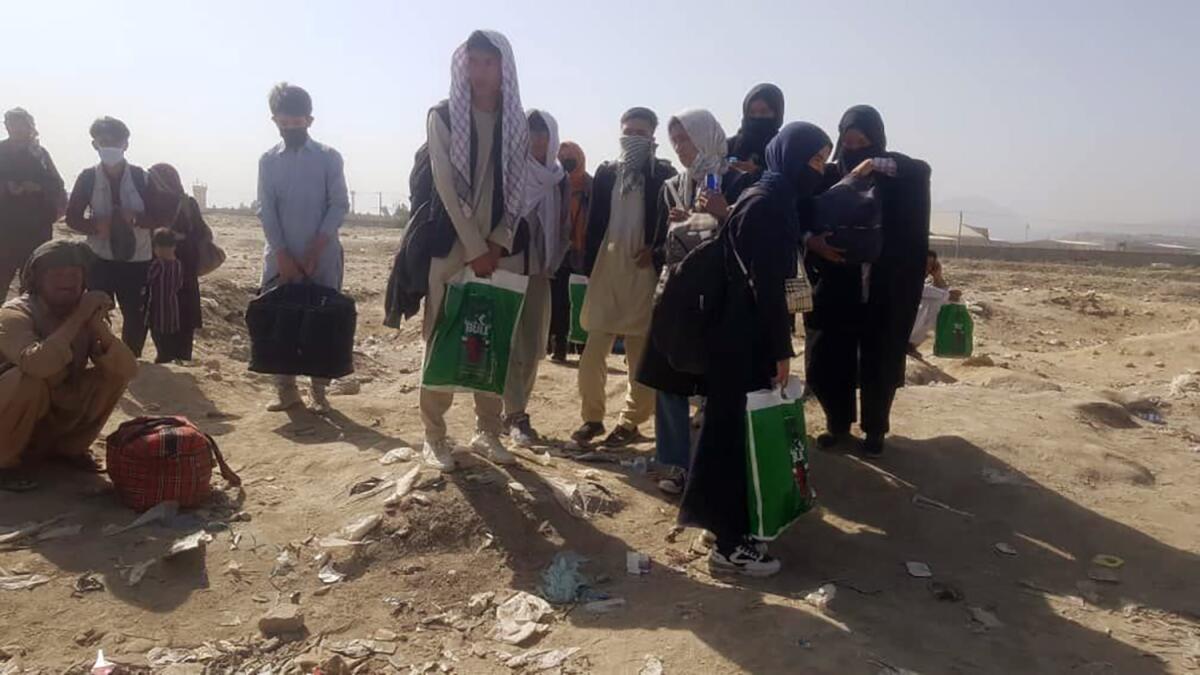 Members of the Afghanistan national girls' youth soccer team and their families are standing and holding bags