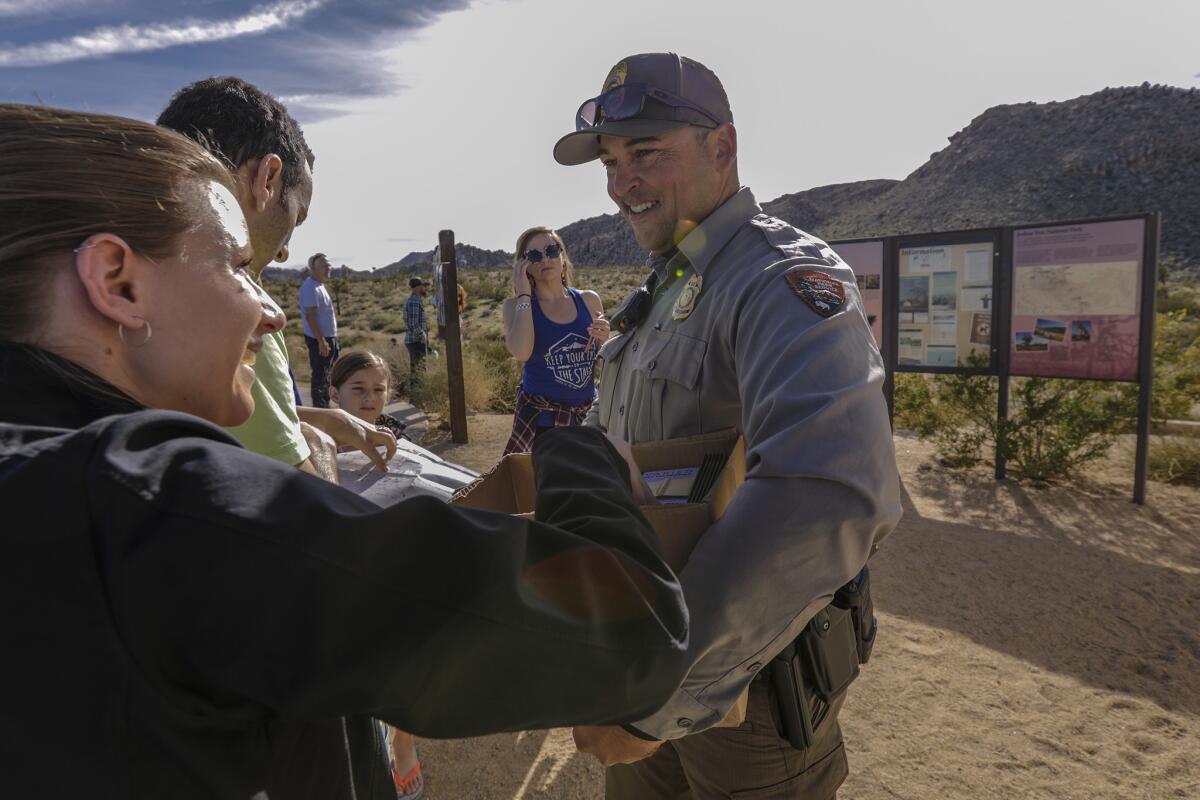 Park ranger Dylan Moe provides park maps to visitors at the entrance to Joshua Tree National Park.