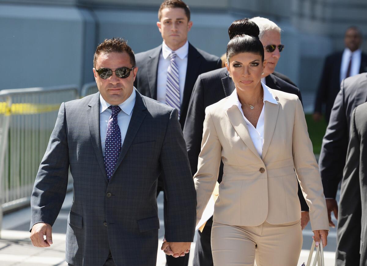 Giuseppe "Joe" Giudice, in suit and tie,  and Teresa Giudice hold hands as they walk along a sidewalk.