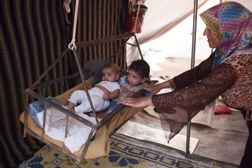 A Syrian refugee rocks her children in a crib at the Bab al-Salam refugee camp in Syria's northern city of Azaz.