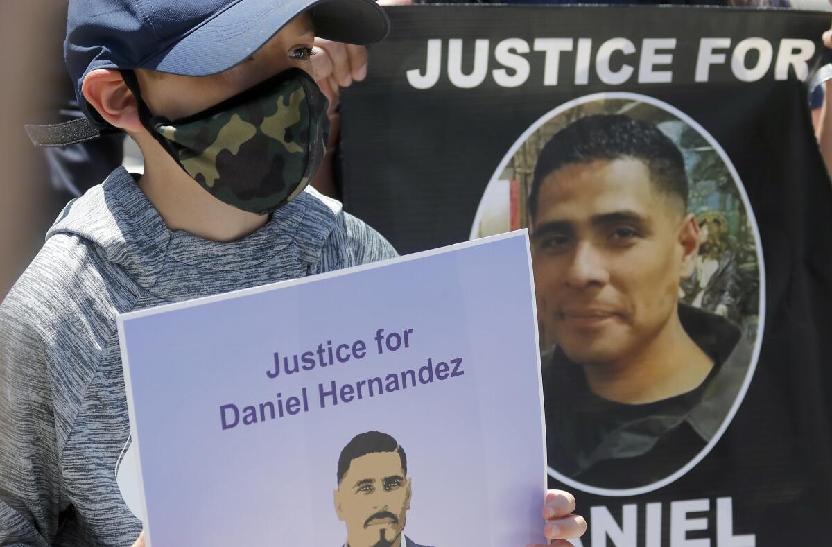 A boy holds a poster with a man's image on it and the words Justice for Daniel Hernandez