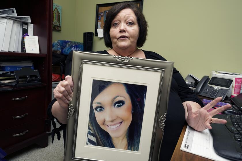 CORRECTS TO DELETE THE MIDDLE NAME AND SAY HARBOUR WAS A VICTIM - Denise Spears holds a portrait of her late step-daughter Marsha Harbour, in her Meridian, Miss., office, Tuesday, April 12, 2022. Although Marsha's husband, Truitt Pace, admitted killing his wife, he was free on bond while court proceedings were partially held up because the Mississippi Medical Examiner's Office autopsy report was delayed for a year, and the trial got held up further because of the pandemic and other factors. Harbour was a victim of domestic violence. (AP Photo/Rogelio V. Solis)