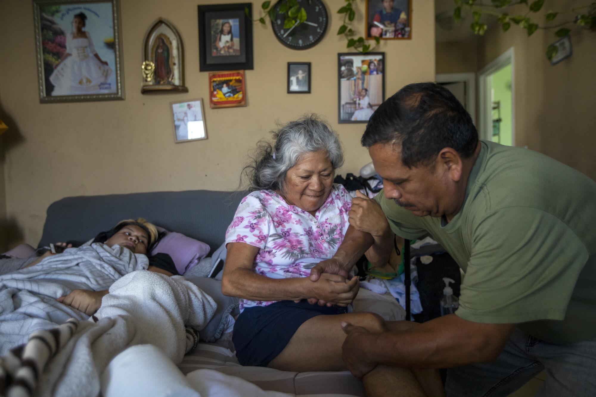 Jose Morales help his wife Reyna out of bed in South Los Angeles.