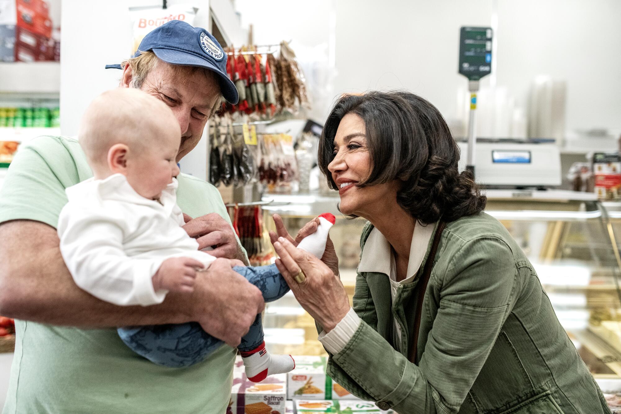 A woman bends down to greet a baby held by a man